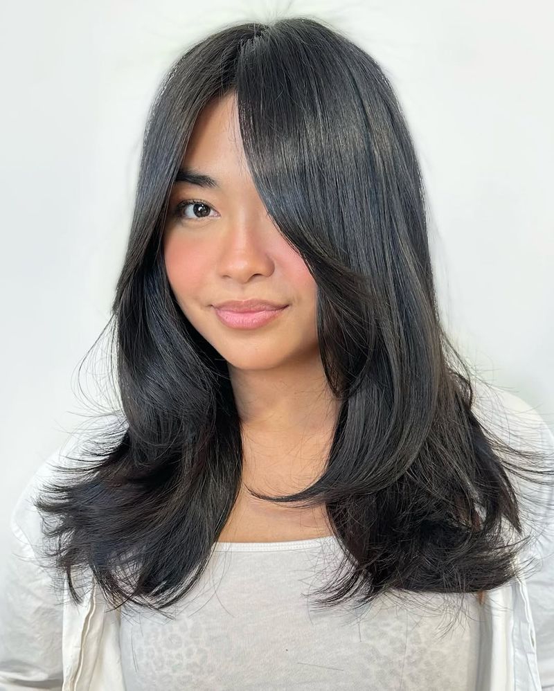 2. Feathered Dark Layers with Sweeping Bangs