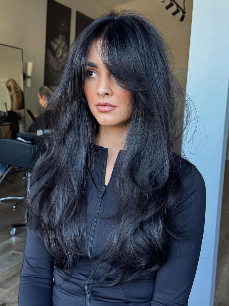 50. Jet Black Layers with Side-Swept Curtain Bangs
